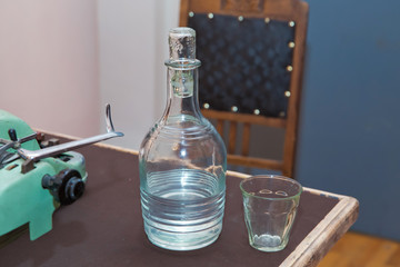 Glass bottle of water with drinking glass . Bottle of liquor on the table . Fresh and clean drinking water in jug and glass . Ancient antique vintage bottle .