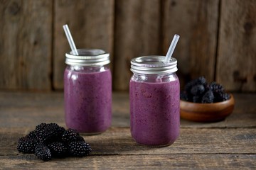 Obraz na płótnie Canvas Healthy blackberry organic smoothie with natural yogurt and honey in a glass jar on an old wooden background.