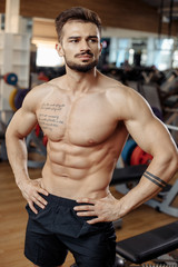 Fototapeta na wymiar Photo of muscular athletic young man bodybuilder fitness model rest after exercises in gym.