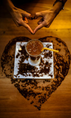 coffee with milk on the table. woman doing heart sign with her hand in cafe 