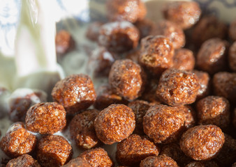 Chocolate cereal balls in milk as food background