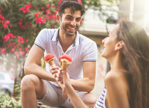 Young couple of lovers chatting and having fun eating an ice cream outdoors