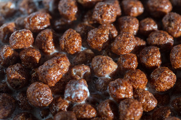 Chocolate cereal balls in milk as food background