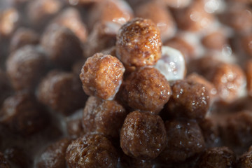 Chocolate cereal balls in milk as food background