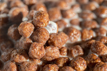 Chocolate cereal balls in milk as food background