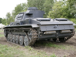 Fototapeta premium German medium tank of the Second World war in working order. the tank is painted black against a background of green trees in summer .