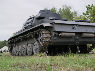 German medium tank of the Second World war in working order. the tank is painted black against a background of green trees in summer .