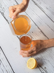 Hands pour a drink from a jug. Kombucha fungus. Organic fermented tea drink.