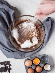 Woman'hand mixing up ingredients for cake made from chocolate and chestnut puree in bowl. Overhead shot.