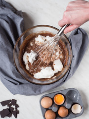 Woman'hand mixing up ingredients for cake made from chocolate and chestnut puree in bowl. Overhead shot.