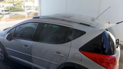 A man in a car wash, washes a dirty car.