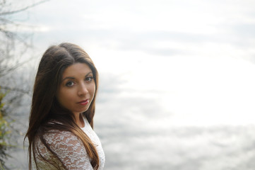 Portrait of a girl with long hair in a white blouse against the background of the water surface