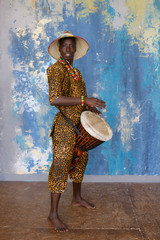 African man in traditional clothes playing djembe drum