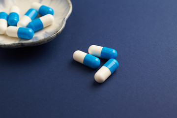 Tri-Creatine Malate capsules. Bodybuilding food supplements on blue paper background. Close up. Copy space. 