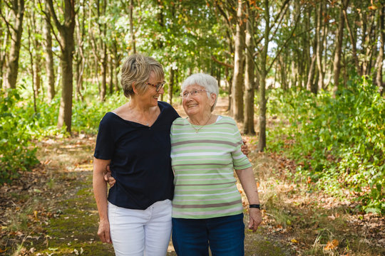 Senior lady with her aged mother with dementia, embracing and smiling in a summer park