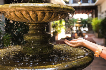 Female hands  ancient fountain with splashing water drops