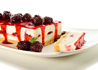 Cheesecake with raspberry jam as topping and raspberries decorating, on a white ceramic plate. For a holiday celebration or party.