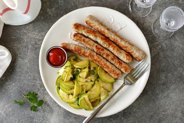 Grilled chicken sausages with zucchini salad in olive oil, soy sauce, wine vinegar, garlic and cilantro. Top view. 