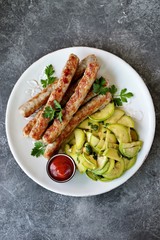 Grilled chicken sausages with zucchini salad in olive oil, soy sauce, wine vinegar, garlic and cilantro. Top view. 