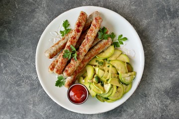 Grilled chicken sausages with zucchini salad in olive oil, soy sauce, wine vinegar, garlic and cilantro. Top view. 