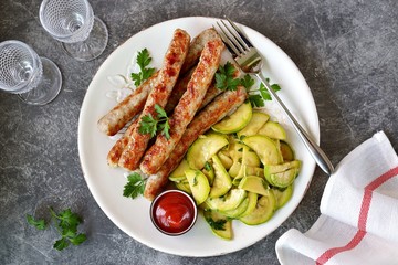 Grilled chicken sausages with zucchini salad in olive oil, soy sauce, wine vinegar, garlic and cilantro. Top view. 