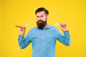 Barbershop offer range of packages for groom. Bearded man work in barbershop. Hipster hold barber tools yellow background. Barbershop concept. Beard shaping and styling in barbershop