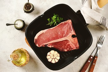 Fresh raw organic beef t-bone steak on a light background. Top view. 
