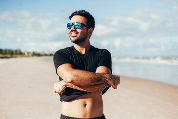 Portrait of smiling handsome man standing on the tropical beach. Summer vacations