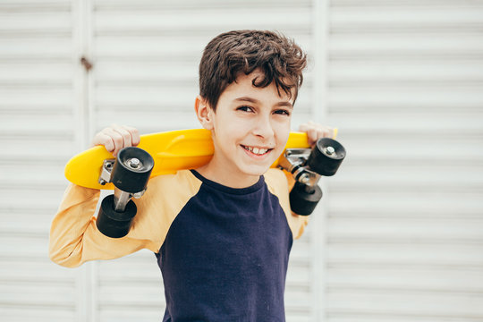 Portrait of 9 year old boy holding skateboard outdoors