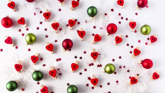 Stop motion animation of advent calender numbers on red hearts beetwen decorative snowflakes and christmas balls of red and green colors and glitter red stars 
