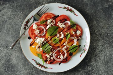 Salad of yellow and pink tomatoes with basil, soft cheese, onions, olive oil and balsamic cream.