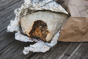 Burrito with a Bite Out of It in Foil and Paper Sack