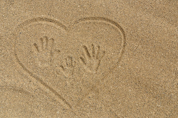 Fototapeta na wymiar Family vacations. Mom's, Dad's and child's handprints trace on the sand in heart.