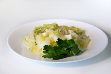 Stewed cabbage with parsley on a white plate