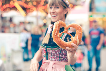 Junge Frau auf der Dult Oktoberfest hält Brezel