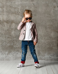 Image of cheerful excited little boy child standing isolated over concrete wall.