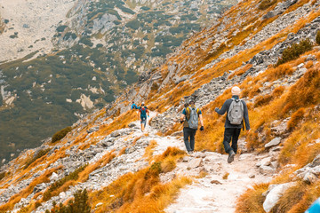 Group of travelers hiking down the mountainside, beautiful autumn mountain landscape