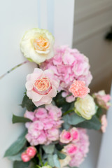 Wedding decorations. Holiday decoration vase with fresh flowers near the wedding arch. Pink roses and carnations