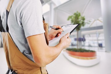 Worker writing on paperclip, close up,on background