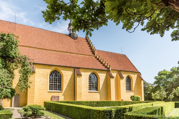 A yellow church with green hedges in Faaborg. It  is consecrated to the holy spirit, Helligåndskirken