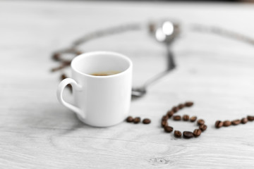 Coffee grains folded in the form of a clock on a wooden background. Instead of the number 7, a cup...