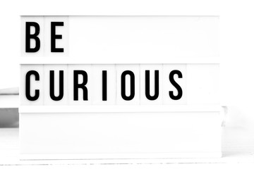 Be curious flat lay on a wooden white background. Motivational business start up board