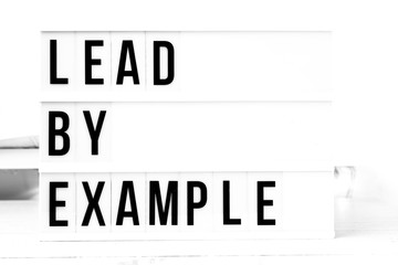 Lead by example flat lay on a wooden white background. Motivational business start up board