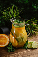 Large carafe with a refreshing and fruit drink on a green background