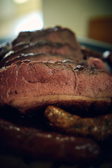 beef sliced and cooked on medium , served on a white plate with sausage and cassava companions