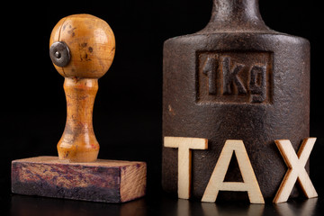 Inscription tax and old weight 1 kilogram. Stamp and store accessories on a dark table.