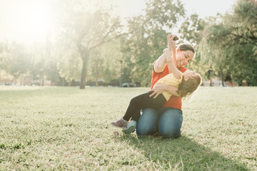 mother and daughter playing on the lawn, laughing