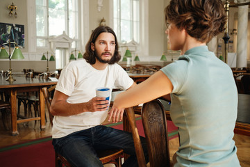 Fototapeta premium Young male student thoughtfully talking with friend during study in library of university