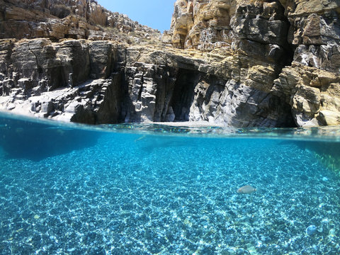 Above and below underwater photo of crystal clear sea paradise rocky seascape full of caves beach of Mouros, Amorgos island, Cyclades, Greece