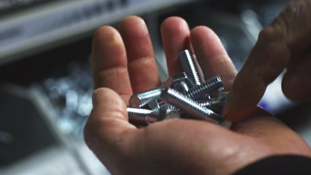 Slow motion close up, hex bolts in hand